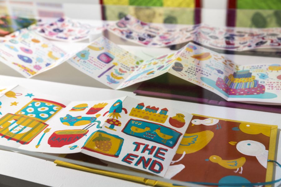 Close up of a book that is yellow, blue, red, on white paper depicting some chickens and household objects and toys, on the bottom right of the page it says "The End" in caps and blue and red letters, the inside book cover is shown on the right with white and yellow birds on a red background, the book seems screenprinted or risograph printed
