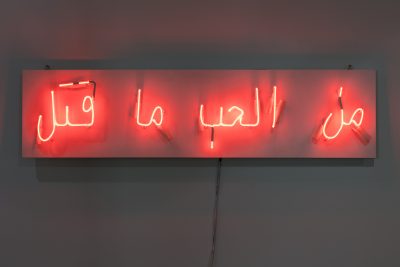 Four neon lights depicting Arabic words installed on a wall.