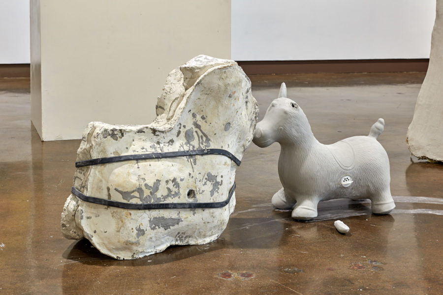 Artworks by Jiajia Li. BFA Fine Arts Exhibition Luminality. SVA Chelsea Gallery, New York. Two sculptures of toy horses, cast out of plaster and clay. The plaster horse has two rubbers straps wrapped around it.