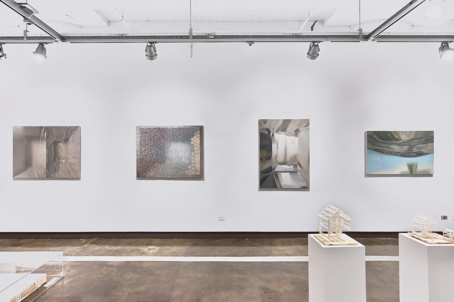 Xinran LiFour paintings depicting metallic and transparent surfaces installed on a white wall, with two pedestals displaying sculptures of a house