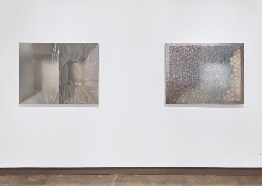 Two paintings depicting metallic and transparent surfaces installed on a white wall
