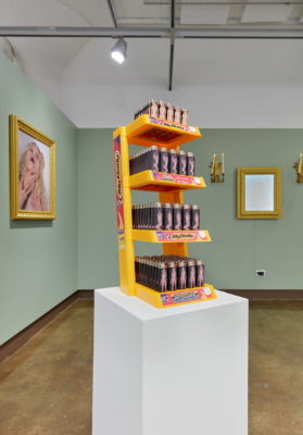 Exhibition Sticks and Stones May Break My Bones But Words Will never Hurt Me 2019. SVA Chelsea Galleries,New York. Installation view. Artwork by Hayley McCormack. Small cigarette lighters with images of a nude female on a retail stand.