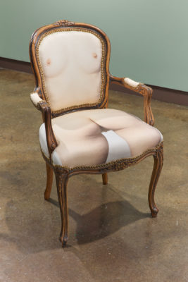 Exhibition Sticks and Stones May Break My Bones But Words Will never Hurt Me 2019. SVA Chelsea Galleries,New York. Artwork by Hayley McCormack. A wooden chair with a nude woman torso printed on the fabric cushion.