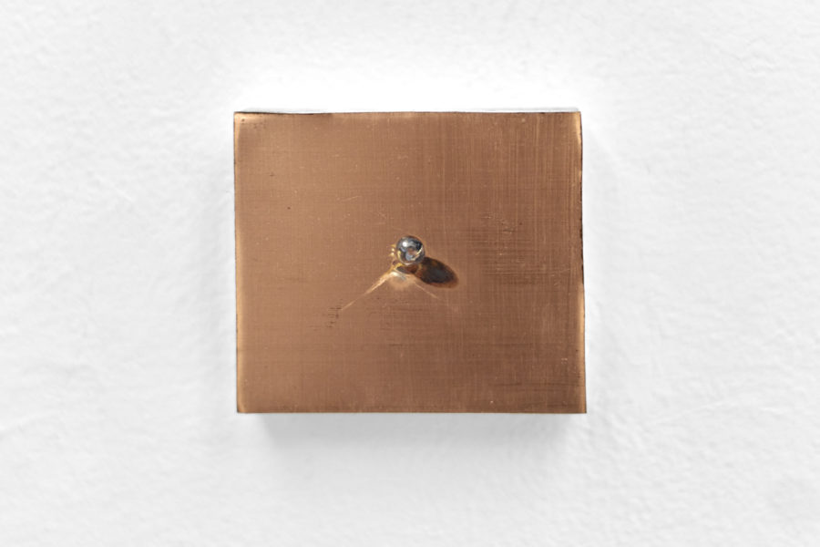 There is a painting with a brown background and a small shiny ball in the center of it