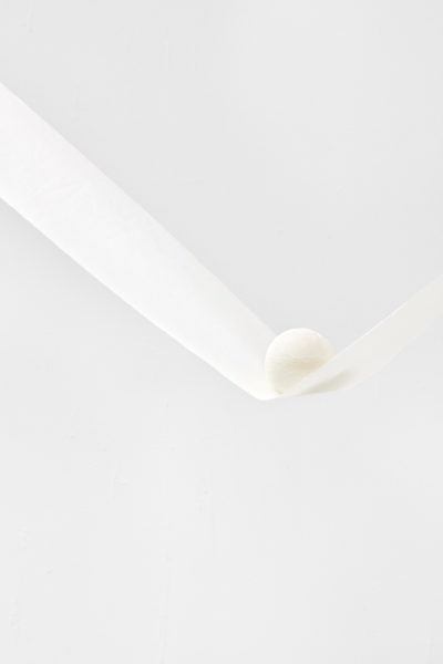 Artwork by Ruofan Chen. BFA Fine Arts, 2019. White spherical object laying on a narrow sheet of white fabric that is attached to the wall.