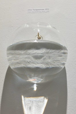 Glass fishbowl mounted to wall with a single orange fish resting at the bottom