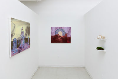 In a white room two paintings hang on a wall and on the opposing wall a shelf holds small sculptures