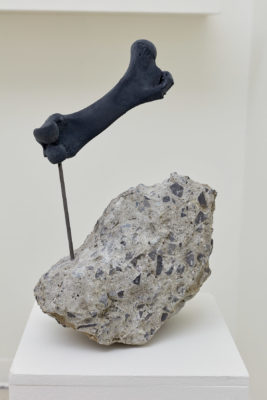 A sculpture made of rock with a bone extruding from it