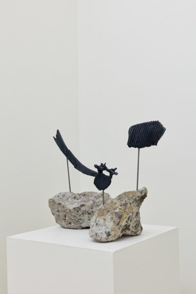 Sculptures made of rock with a bone extruding from them rest on a pedestal