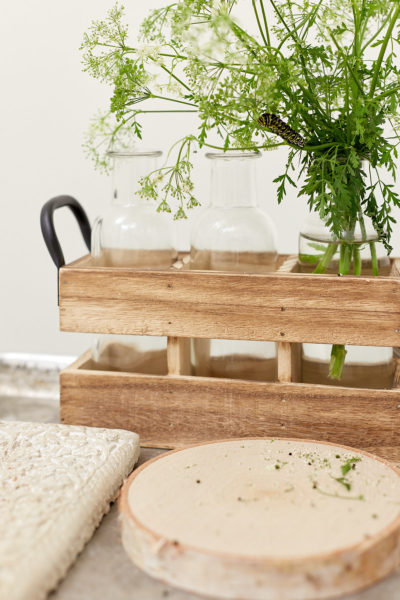 Wooden trays holding glass bottles and fresh cut greenery