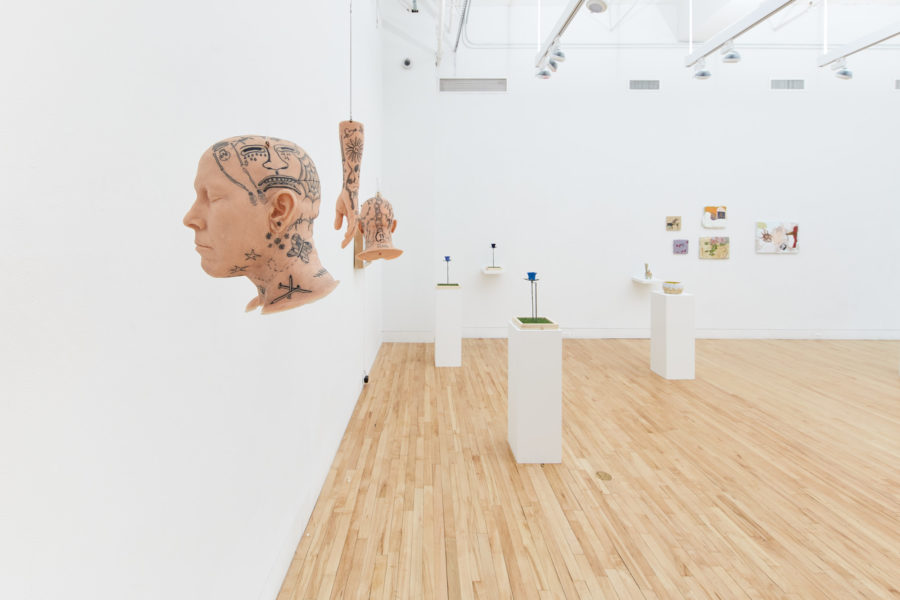 Exhibition Tales and Whispers 2019. SVA Flatiron Gallery, New York. Installation image featuring multiple paints of figures. In the center of the room there are multiple sculptures placed on top of a pedestals.