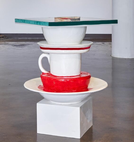 Large sculpture of a pile of plates and cups painted in white and bright red