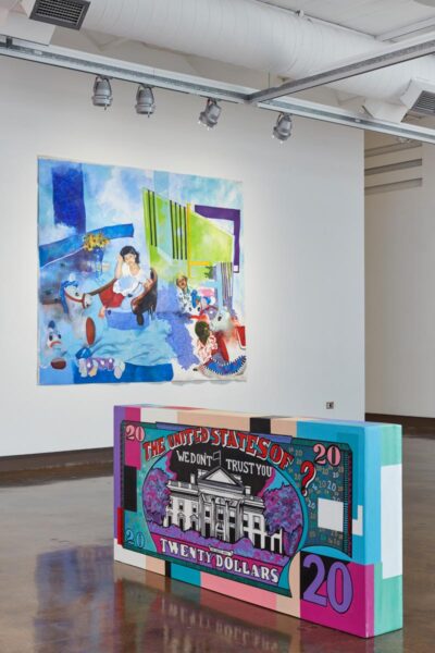 Installation view with a large colorful bill note on the floor and a large portait painting in the background.