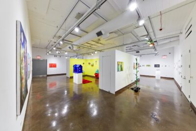 Installation view of vivid colored paintings on the wall and sculptures installed on the floor and the pedestal