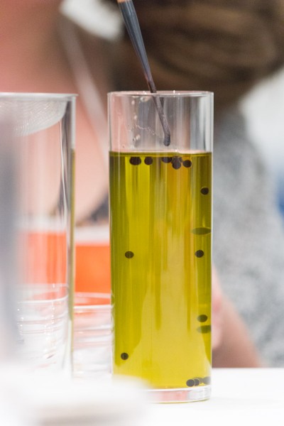 Drops of black vinegar being submerged in a lab container with olive oil during a class workshop.