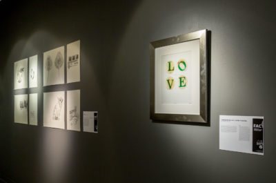 Framed prints on a wall, the foremost of which spells out LOVE