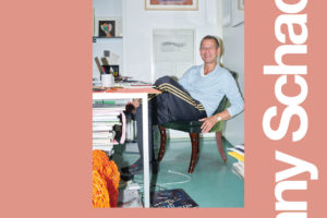 Poster for Kenny Schachter's lecture at SVA on November 7, 2019. The poster is salmon colored with white text. A photo of Schachter sitting at a desk is placed in the center of the poster.