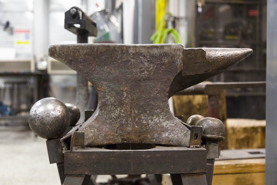 A close-up of an anvil made of iron and a few iron balls on the left side and the right side of the anvil