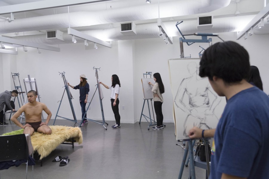 Drawing class with students at their easel and drawing a sitting model