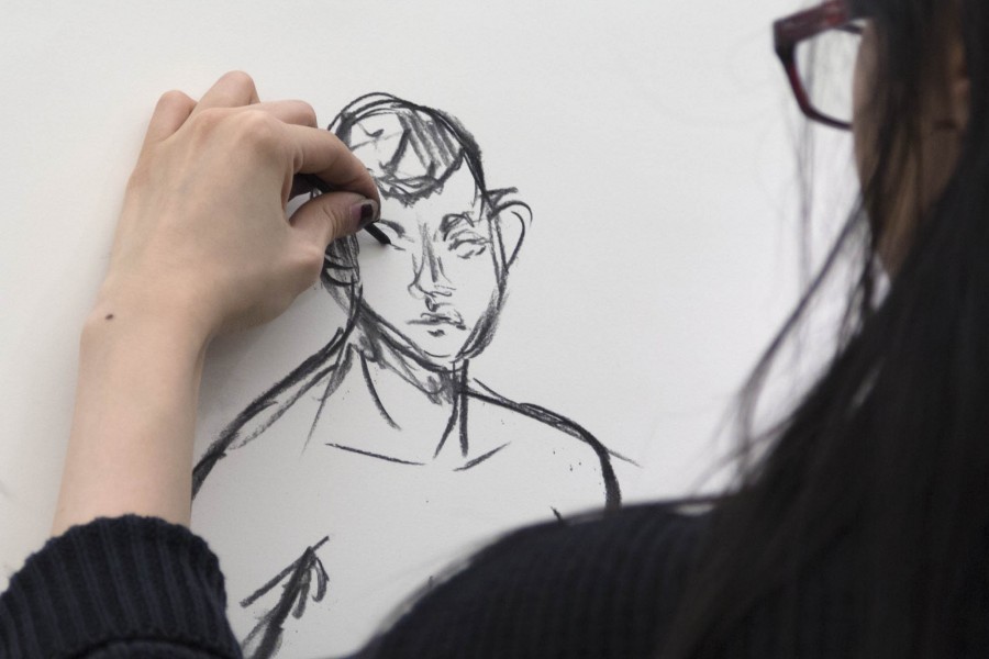 Close view of an SVA student drawing a male model with graphite