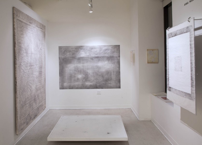 Installation view of three paintings with different textures on them, colored in shades of grey.