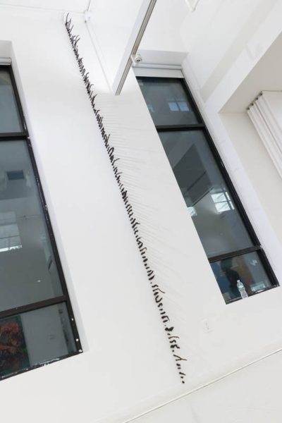 Installation view of a column made on a wall with human hair, between two windows