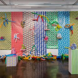 Installation view of sculptures made from organic fabric materials and Christmas present paper wraps installed on the wall in the background