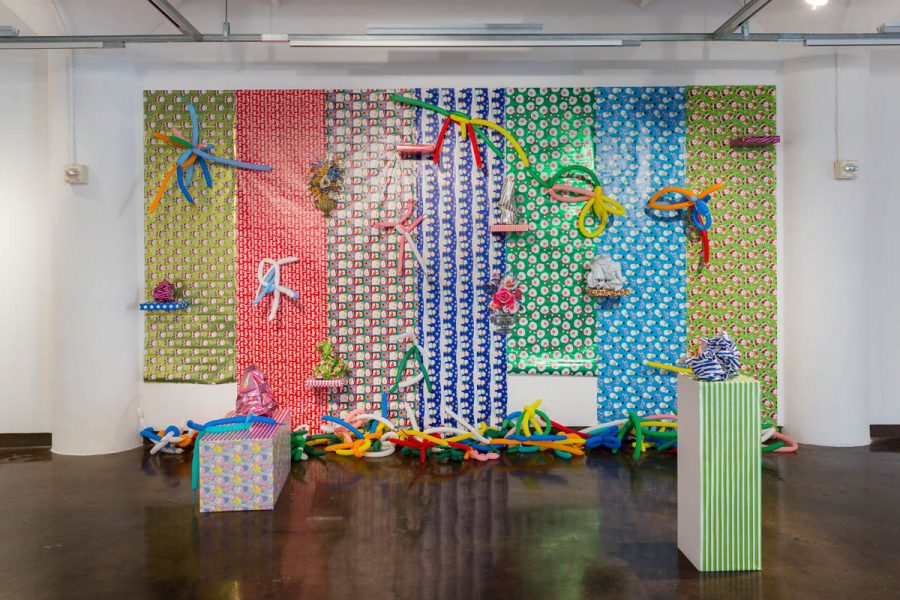 Installation view of sculptures made from organic fabric materials and Christmas present paper wraps installed on the wall in the background