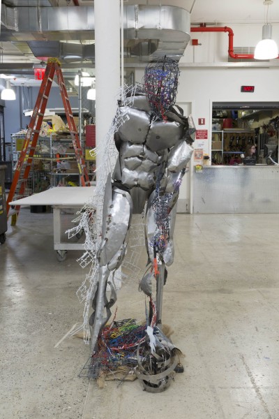 Frontal view of an anthropomorphic sculpture made of metal and colored plastic mesh