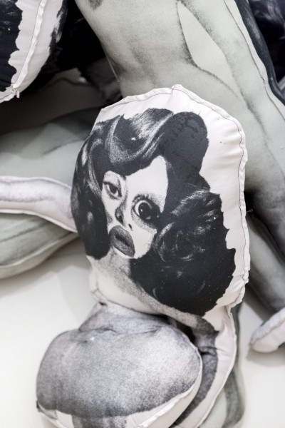 Close view of a pillow with a print of a nude woman and disproportioned eye size.