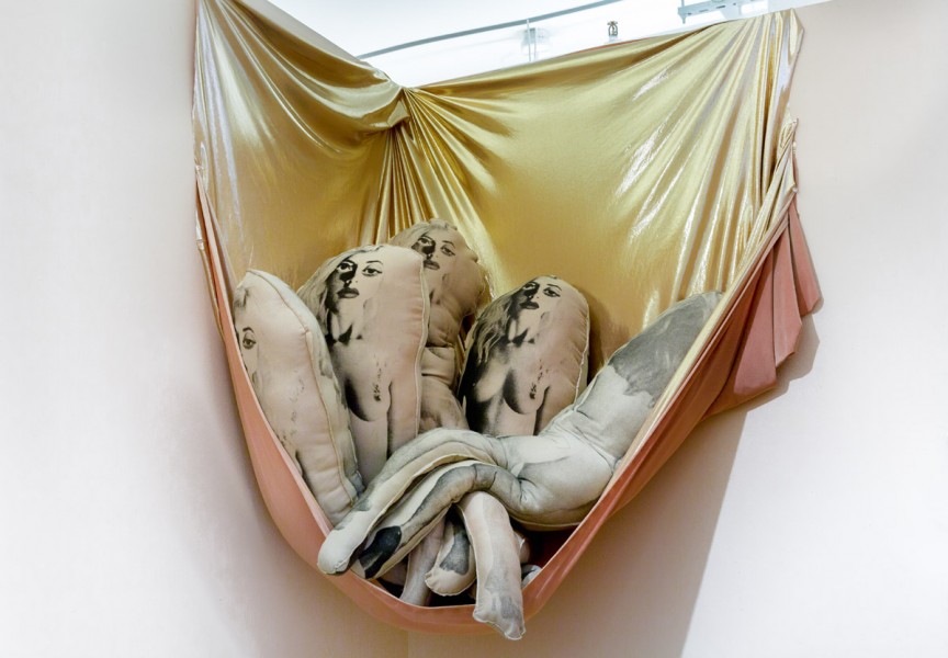 Detailed view of silkscreen stuffed with nude women print on them placed in a golden hammock by Alexa Keshtgar