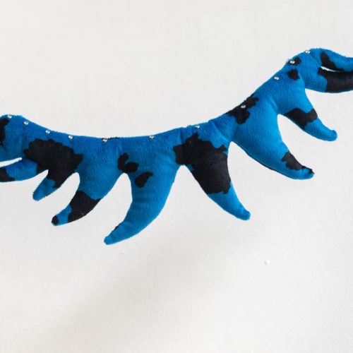 A piece of organic fabric cochin made in the shape of teeth from a blue material with black spots, suspended in the air with an invisible line