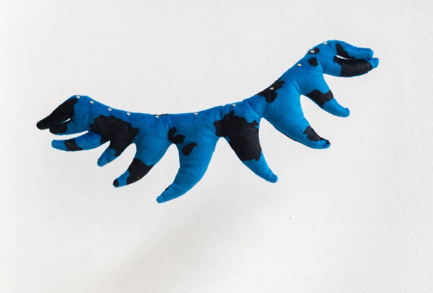 A piece of organic fabric cochin made in the shape of teeth from a blue material with black spots, suspended in the air with an invisible line