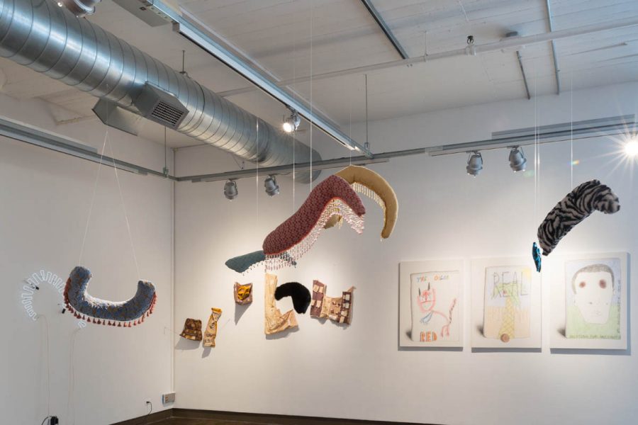 Hanging sculptures made of organic fabrics and suspended with invisible lines are installed in a room with a few paintings on the wall in the back