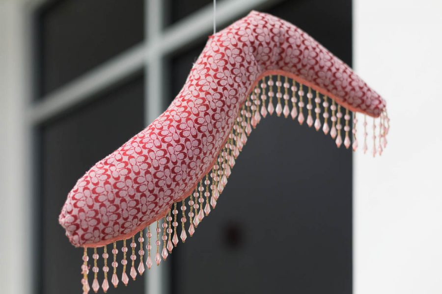 A sculpture made of organic red fabric with tassel, suspended in the air with an invisible line