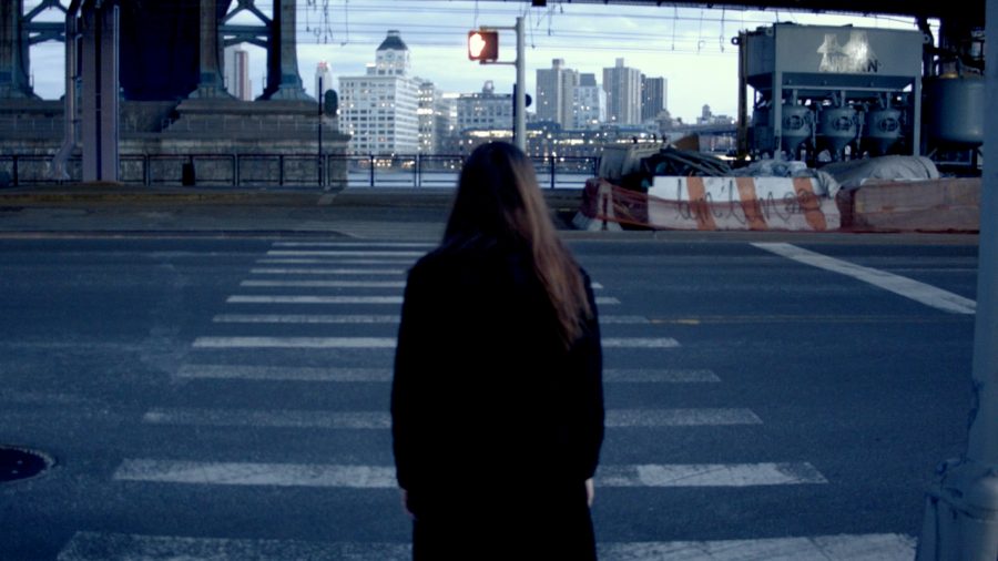 Artwork by Alexandra Russo. Still video image of a figure in front of a cityscape.