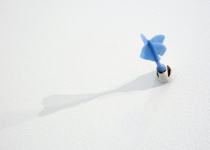 A blue dart installed on a white wall.