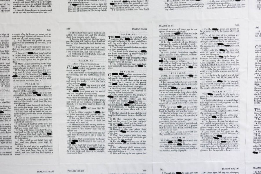 A view of Psalms pages from the bible with words censored with a thick black marker