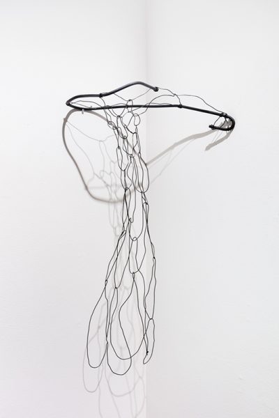 Sculpture by Andrew Lee. A circular broken wire ring attached to the wall with a woven wire net attached flowing toward the floor.