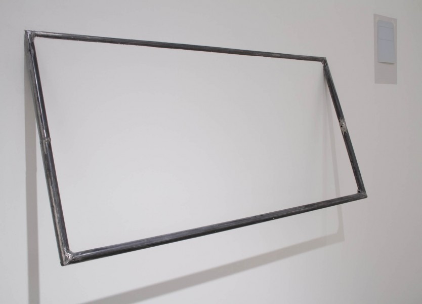 A view of a rectangle shape made of metal rods welded together and installed on the wall with the top part stuck on the wall, and the bottom part is at a distance from the wall
