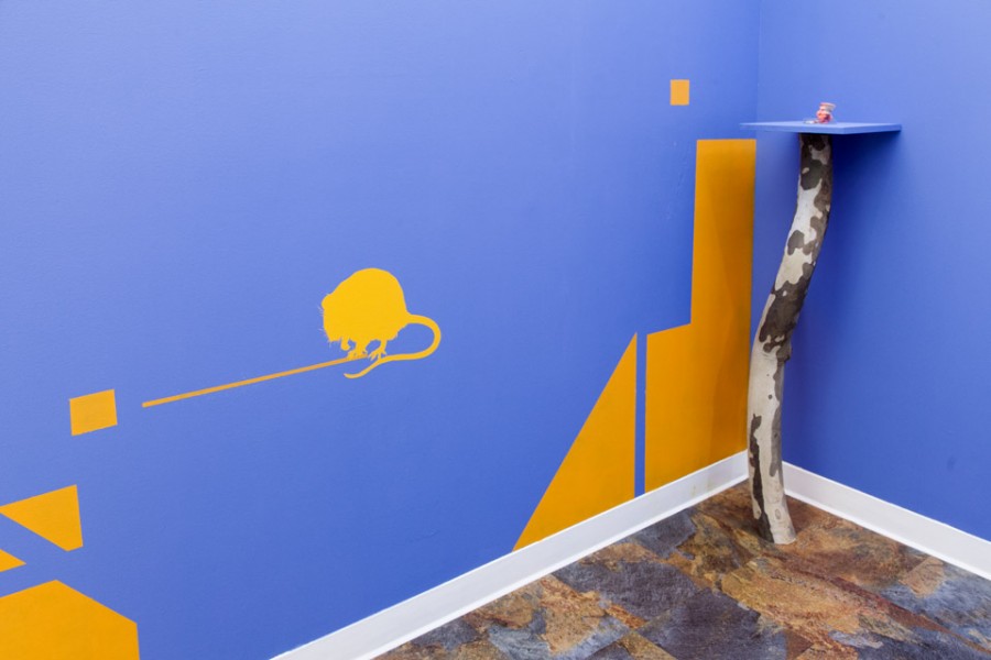 Close view of a curved stand in a corner and yellow geometric shapes on the wall with blue background.