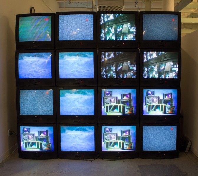 A grid of CRT TVs, some with images on the screen and some with a static black image.