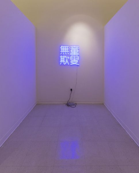 Studio lit in blue light from a neon sign depicting Chinese characters.