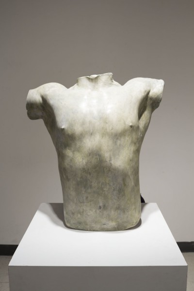 Bust sculpture made of white-grey material of a male body without the head and the hands