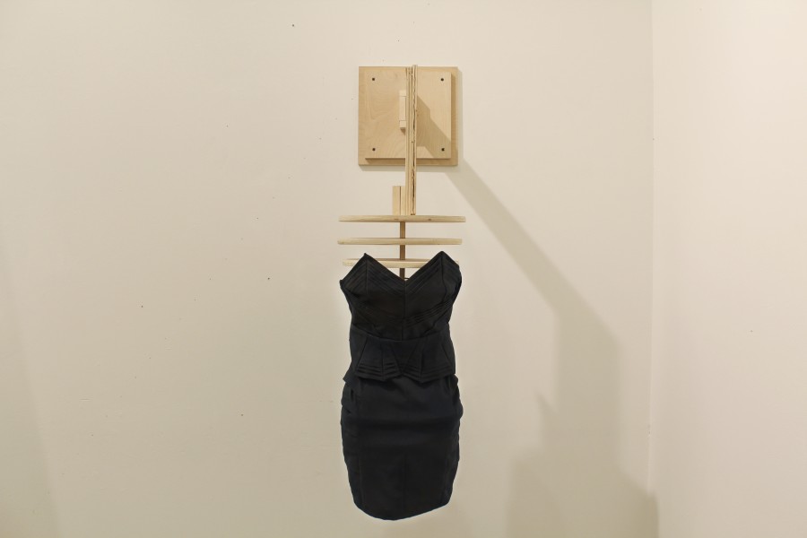 Installation of a black dress made of fabric and installed on wood support imitating the rounded body shapes of a woman's body