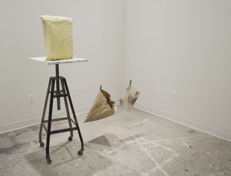 Installation of a paper bag on a shelf, a paper bag, and a print hung with hangers-on a thread