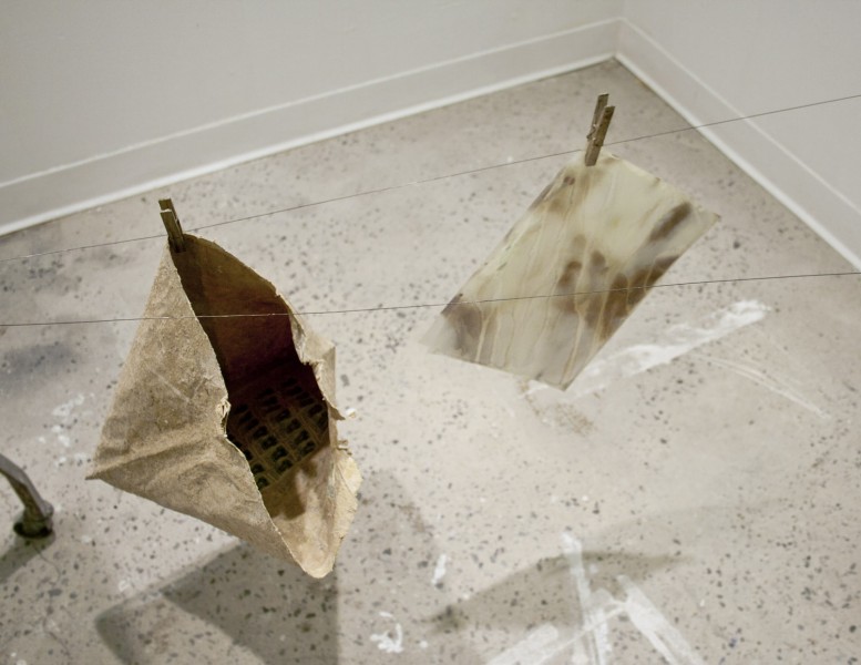 A paper bag hung with a hanger on a thread line and a photograph hung near it