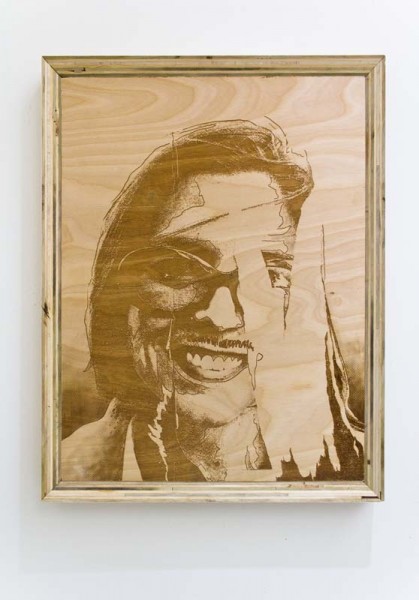 Portrait print of a person on a wood surface, with half of the face, covered, wearing glasses and long hair
