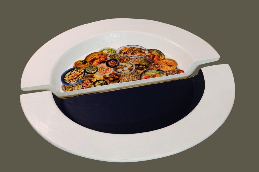 An sculpture of plate splitted in half, with one part painted in black and the other with a printed collaged of food plates.