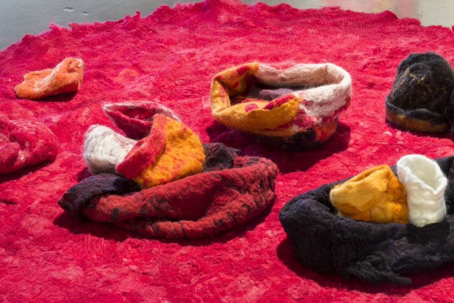 Many different rounded shaped objects made out of fabrics lay on a red carpet